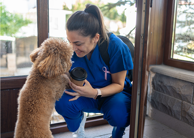 Nurse greeting dog with coffee cup.