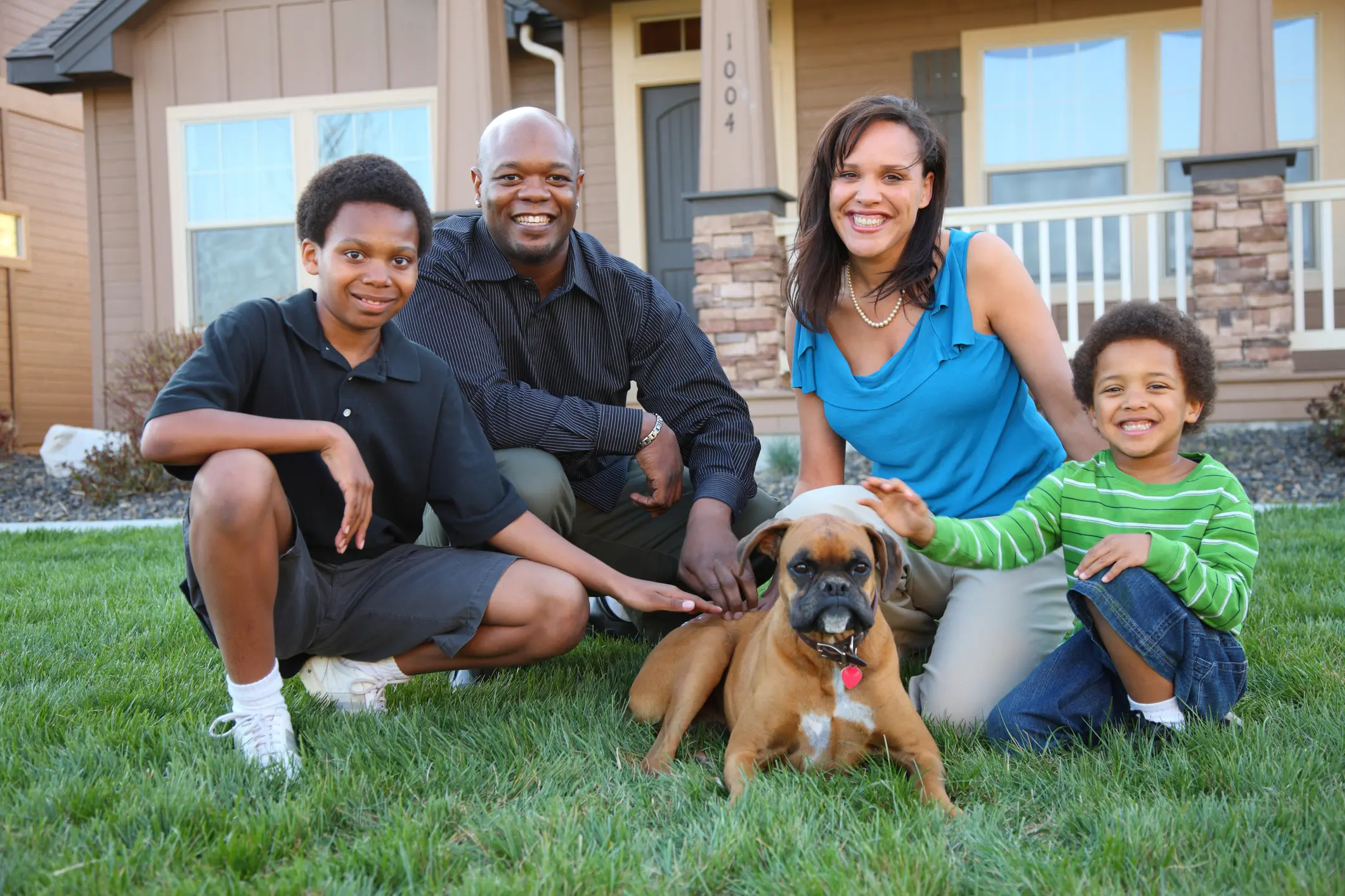 Family with dog posing in front yard.
