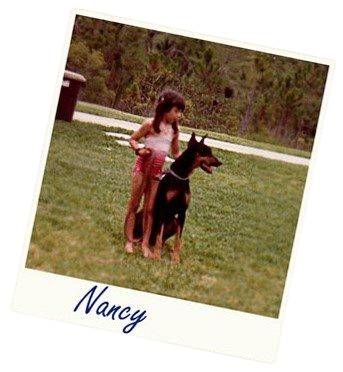 Young girl standing with a Doberman dog.