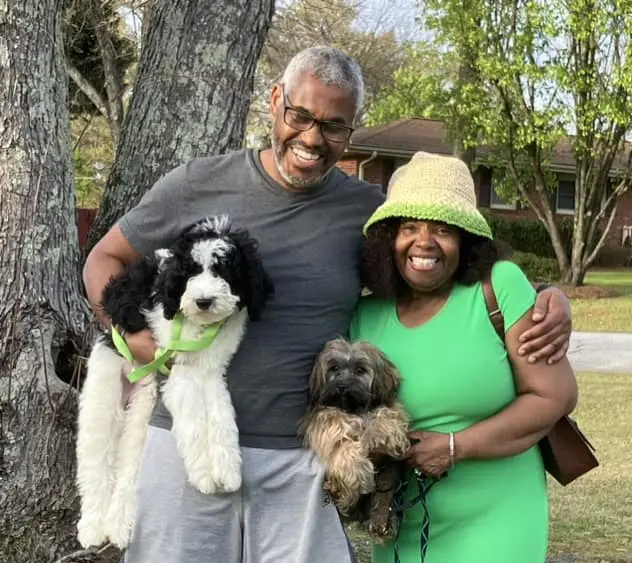 Smiling couple with two dogs outdoors.