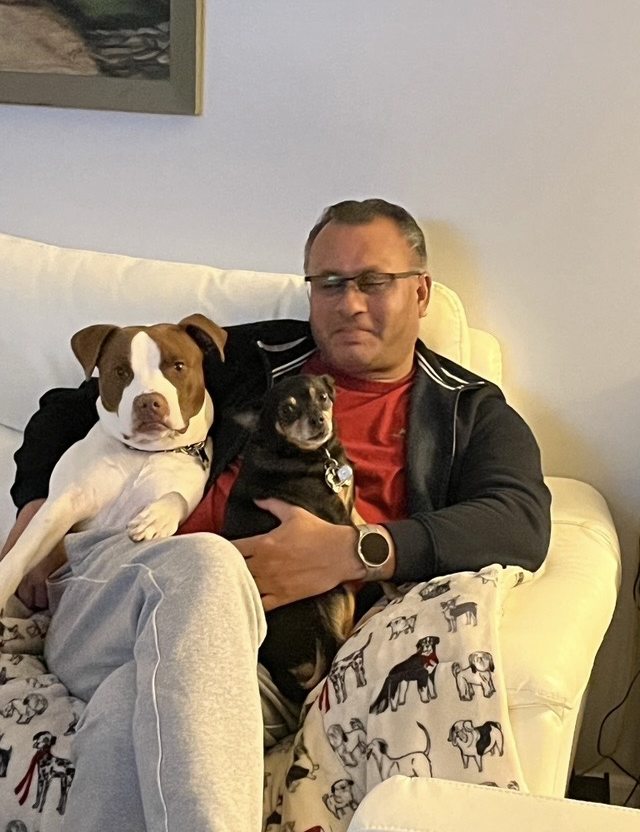 Man sitting with two dogs on couch.