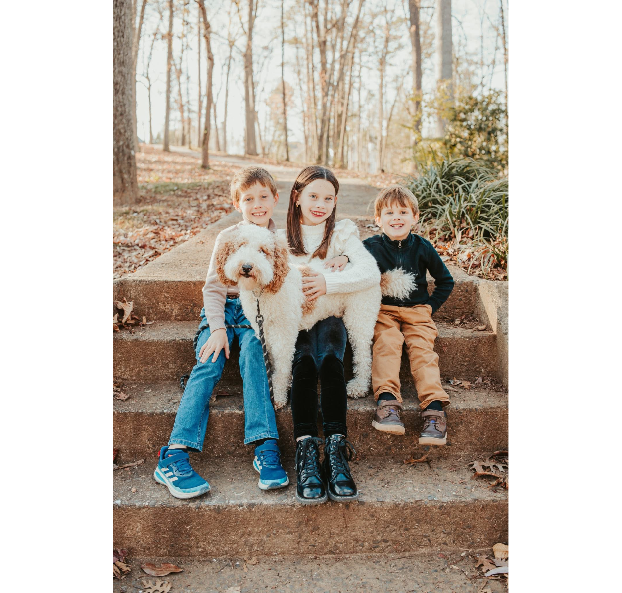 Three children sitting on steps with dog