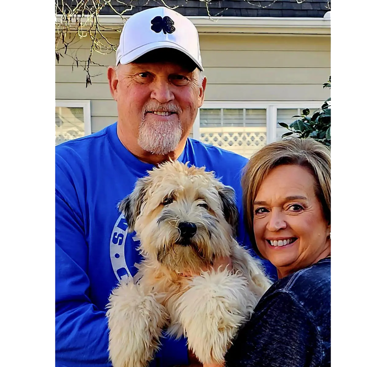 Smiling couple holding fluffy tan dog