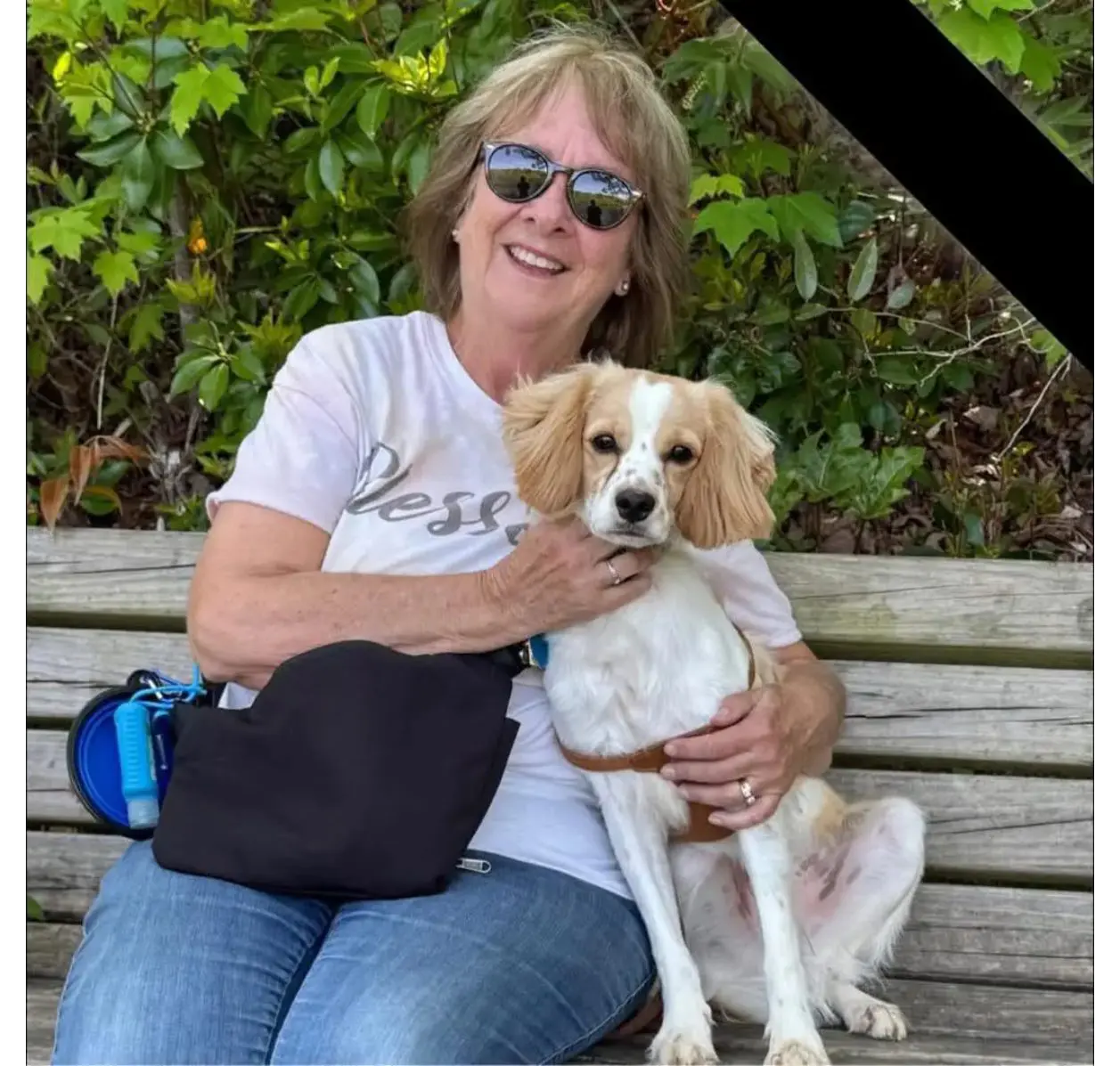 Smiling woman with sunglasses holding tan-and-white dog