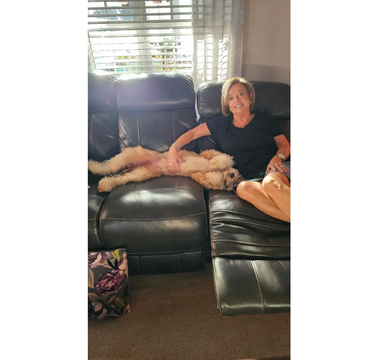 Smiling woman on couch with sprawled dog