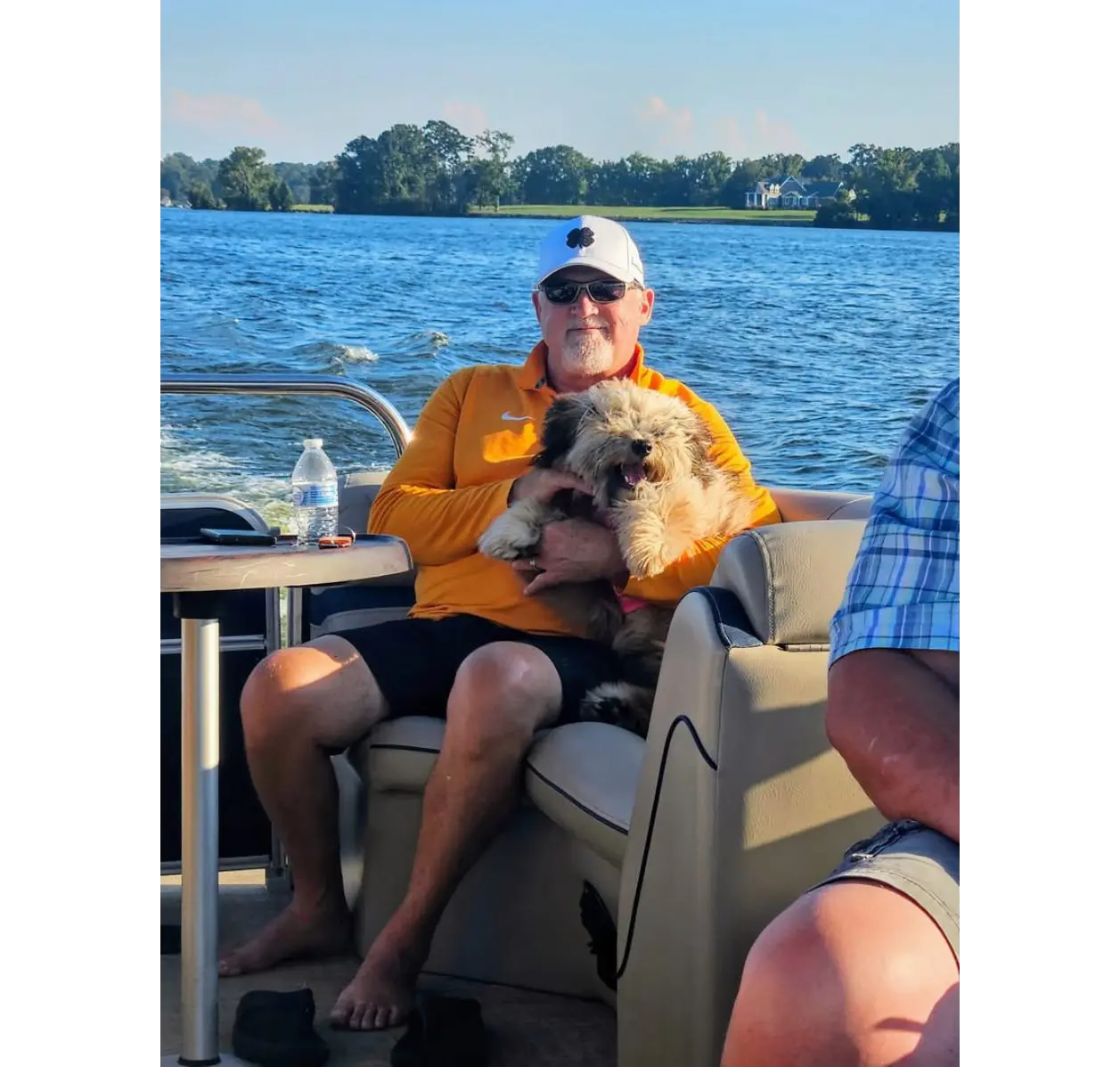 Man holding fluffy dog on lake boat