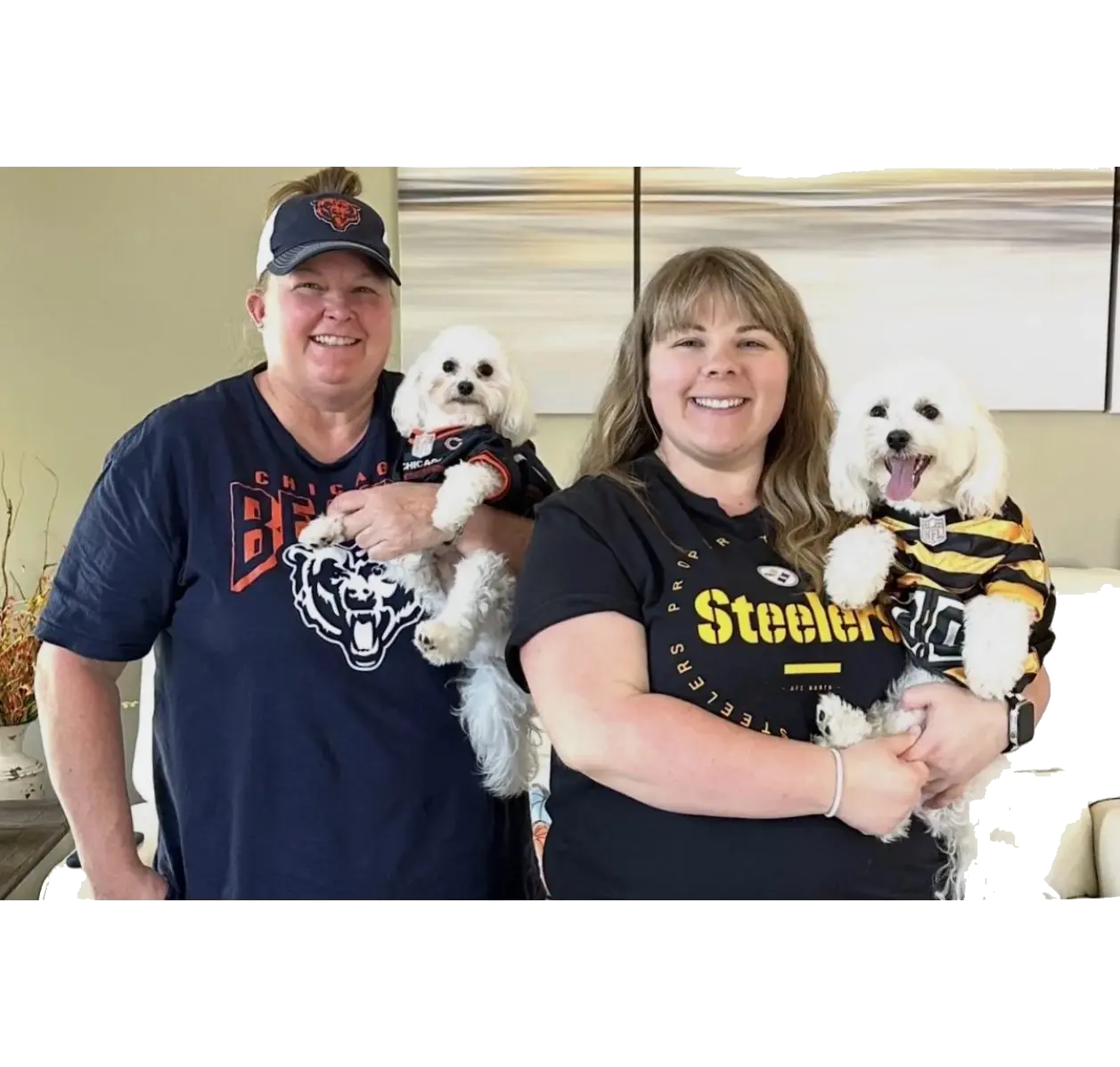 Two people holding small white dogs in jerseys
