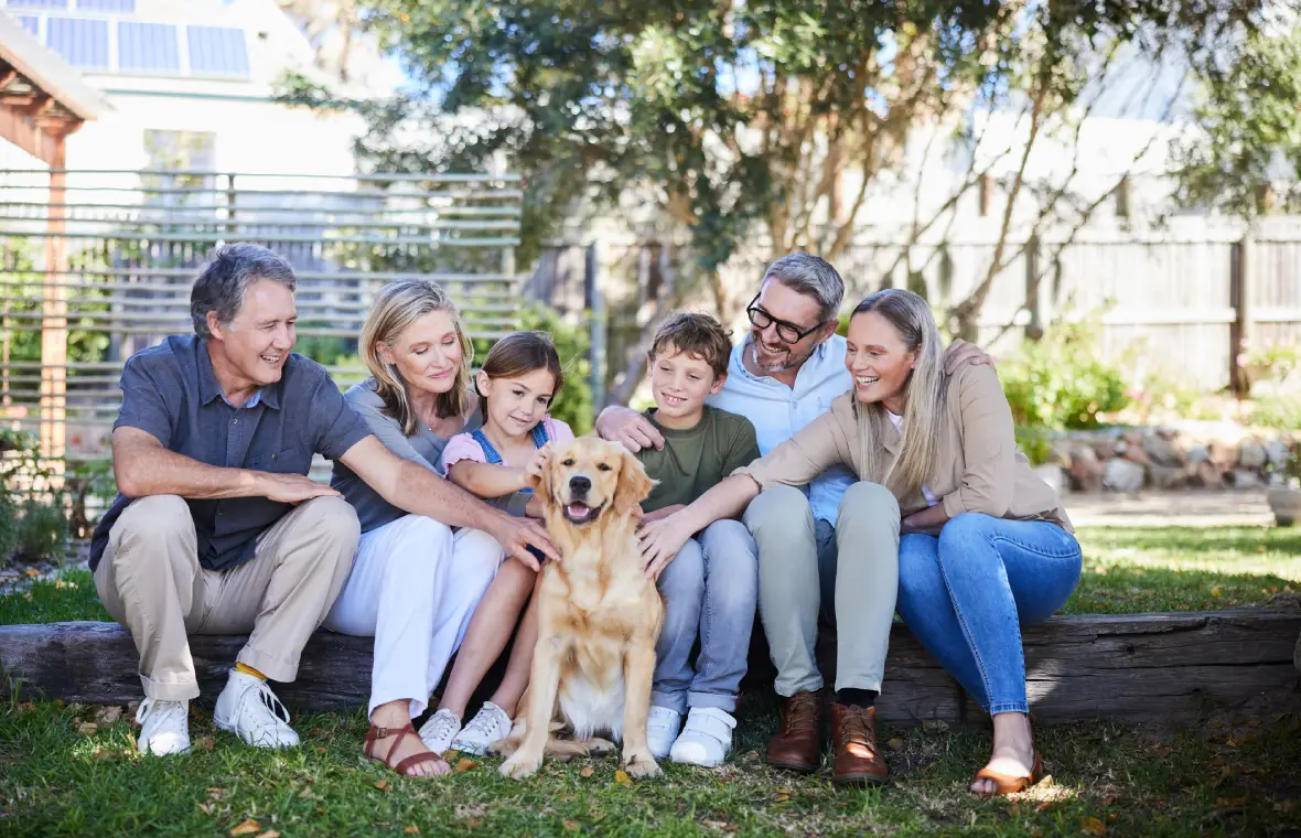 Family sitting outdoors with a golden retriever.