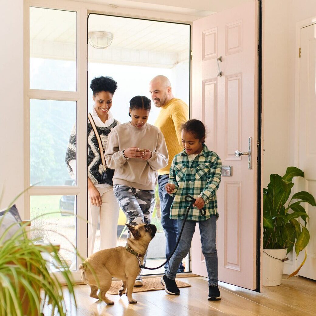 Family entering home with their small dog.